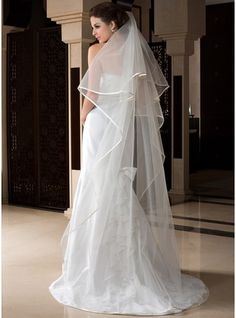 a woman in a white wedding dress with a long veil on her head and shoulders