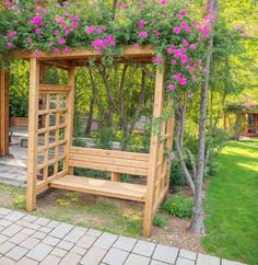 a wooden bench with pink flowers growing on it