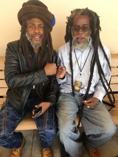 two men with dreadlocks sitting on a bench