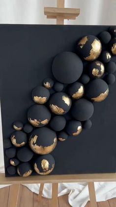 a painting with gold and black balls on it