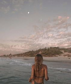 a woman is standing in the water at the beach