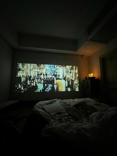 a large screen is projected on the wall above a bed in a dimly lit room