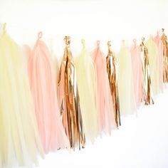 tissue tassels are hanging on a line with gold and light pink streamers