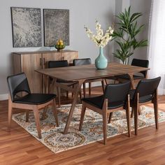 a dining room table with black chairs and a blue vase