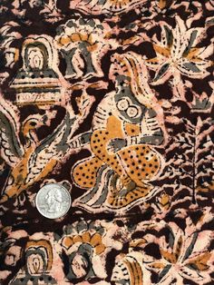 a coin sitting on top of a piece of cloth covered in animal and flower designs