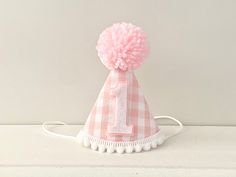 a pink and white hat with the number one on it's side sitting on a table