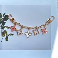 a close up of a chain with charms on it and a plant in the background