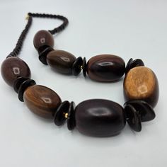 Vintage single strand wooden necklace. 24 inch statement piece. Large pieces of natural wood grouped with smaller wooden beads.  The wood in this piece represents the many colors of natural wood pieces. They range from a dark ebony color to a light brown. Each piece on the necklace is unique and makes a stunning piece of vintage jewelry when grouped together. The larger beads are 1 inches long X 3/4 of an inch wide. The smaller wood beads are 0.25 inches around. Vintage Wooden Beads Necklaces, Mahogany Wooden Beads Jewelry, Mahogany Colored Wooden Bead Jewelry, Artisan Natural Wood Necklaces, Natural Wood Necklaces With Wooden Beads, Earth Tone Jewelry, Ebony Color, Wooden Necklace, Wood Necklace