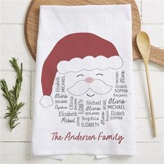 a tea towel with a santa claus face on it next to a wooden spoon and sprig of rosemary