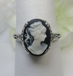 Cameo Ring Edward Design#70 Custom Made Here we have an Edwardian reproduction ring in sterling silver filigree with a variety of resin cameo options, choose from a black, light blue, or light pink lady silhouette, or an deep-orange daisy flower, or a light blue Bell flower. These beautiful cameos measure 14mm in length and 10mm in width. This ring also sits 7mm off the finger. The inside of the band is marked 925 for solid sterling. Notice the beautiful leaf and floral design of the filigree se Adjustable Gothic Rings, Silver Gothic Cameo Jewelry, Carved Sterling Silver Jewelry For Wedding, Carved Sterling Silver Wedding Jewelry, Victorian Carved Silver Jewelry, Victorian Style Carved Silver Jewelry, Victorian Silver Carved Rings, Handmade Victorian Style Rings, Victorian Carved Silver Rings