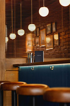 an empty bar with stools in front of it and several lights hanging from the ceiling