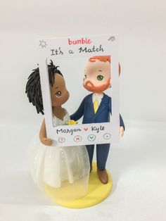 a wedding cake topper with a bride and groom holding a sign that says bumble it's a match