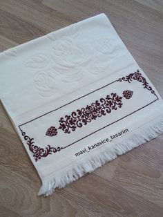 a white towel with brown designs on it sitting on top of a wooden floor next to a pair of scissors