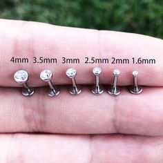 five pairs of silver nose studs are shown in the palm of someone's hand