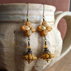 Lovely Czech glass flower earrings in a pretty butternut orange color. For these, I chose a pair of beautiful and unique four-pointed flower beads, and paired them with bell flowers in a similar shade, which I hung below them. Both beads are a beautiful butternut orange with gold accents. I paired them with antiqued brass and some small orange beads to accent their beauty, then hung them from simple French earwires. These earrings measure just over 2 1/2 inches, or about 6.5 cm, including the French earwires. (They are also available with leverback earwires if you prefer, which are a similar length to the French ones.) All of the beads are Czech glass, and all of the metal is antiqued brass or antiqued brass-plated. Vintage Orange Earrings With Czech Glass, Orange Flower-shaped Adjustable Earrings, Vintage Orange Czech Glass Earrings, Gold Flower-shaped Czech Glass Earrings, Gold Flower-shaped Earrings With Czech Glass, Nickel-free Orange Flower Earrings, Gold Flower Earrings With Czech Glass, Orange Adjustable Dangle Flower Earrings, Vintage Gold Flower Earrings With Czech Glass