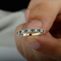 a person is holding a ring with blue and white stones on the inside of it