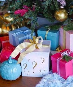 presents under a christmas tree with question marks on them and ornaments around the gift boxes