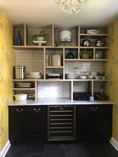 a kitchen with black cabinets and yellow wallpaper on the walls is pictured in this image