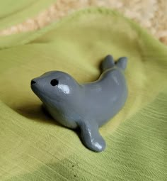 a gray seal toy laying on top of a green blanket