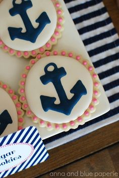 three decorated cookies with blue and pink icing are on a striped napkin next to a card