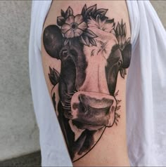 a black and white cow with flowers on it's head is shown in this tattoo