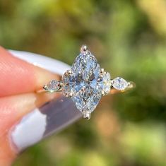 a woman's hand holding an engagement ring with three diamonds on it and the center diamond in the middle