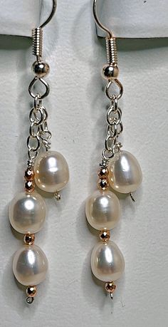 Take three pure white freshwater pearls per earring, attach them to sterling silver chain, and dangle them from French wires. That's the recipe for beautiful earrings that will go with everything. Just for fun, add in a few tiny rose gold beads; that's the finishing touch. These earrings have a 1 1/2 inch drop, and are 2 3/8 inches long overall. Sterling Silver White Pearl Earrings With Pearl Chain, White Sterling Silver Pearl Chain Earrings, Sterling Silver White Pearl Chain Earrings, White Pearl Chain Earrings In Sterling Silver, White Nickel-free Dangle Pearl Earrings, Unique Diy Earrings Ideas, Easy Diy Earrings, Diy Earrings Pearl, Handmade Earings