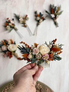 a person holding flowers in their hand near some hair pins on the wall behind them