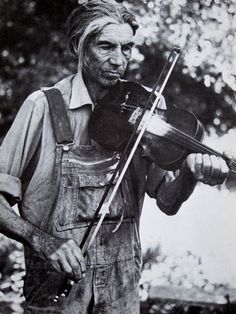 an old black and white photo of a man holding a violin in his right hand