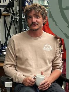 a man sitting in a chair holding a coffee cup