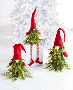 three elfs are standing next to a christmas tree in front of a white background