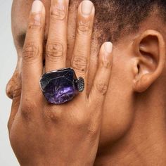 a close up of a person wearing a ring with a stone on it's middle finger