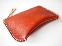 Simple yet unique formed zipped pouch.Using two types/colours of vegetan leather.Has a inside pocket.Able to use as a cosmetic bag, clutch bag, wallet, travel wallet and more.- Made from 100% Vegetable tanned leather- Hand stitched with waxed thread- Edges are burnished to smooth sheen- YKK metal zipper- Comes with 100% cotton bagApproximate Dimensions: W 8" x H 5" x D 1.50'' W 20cm x H 13cm x D 4cmZipper length: 7"18cmPersonalisation (optional)- Complimentary personalisation is available.- You Leather Pouches, Leather Zipper Pouch, Leather Zip Pouch, Small Leather Wallet, Leather Clutch Bag, Leather Card Case, Leather Coin Purse, Travel Wallet, Leather Hats