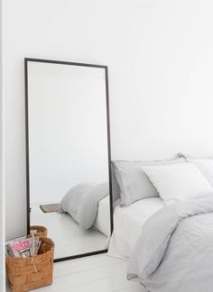 a bedroom with a large mirror on the wall next to a bed and a basket