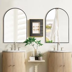 two oval mirrors are above the sink in this bathroom with bamboo cabinetry and white walls