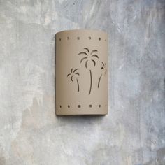 a wall mounted light on the side of a building with palm trees painted on it