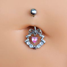 Product DetailsClear Pink CZ Gem Heart Wreath of Love Belly Ring Deck your body with a wreath of love - like this 14 gauge navel ring. It's made with a 3/8 inch 316L surgical grade stainless steel curved barbell with a 5mm top ball end. The bottom end features a festive wreath charm with a bow embellishment at the top and clear cubic zirconia gems all along the bottom. The wreath is further embellished by a dangling pink cubic zirconia gem heart. No matter what the season, why hang a wreath on y Heart-shaped Pink Belly Rings For Gift, Pink Heart-shaped Belly Rings For Gift, Silver Heart Belly Rings For Valentine's Day, Valentine's Day Silver Heart Belly Rings, Adjustable Body Jewelry For Valentine's Day, Silver Belly Rings For Valentine's Day, Valentine's Day Gift Silver Belly Rings, Heart-shaped Silver Body Jewelry For Wedding, Cubic Zirconia Belly Rings For Gift