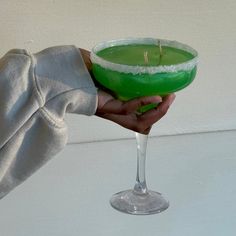 a person holding a green drink in their hand