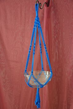 a glass bowl hanging from a hook on a red wall with a pink curtain behind it