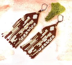 two brown and white beaded earrings sitting next to each other on top of a table