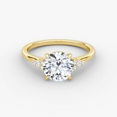 a yellow gold engagement ring with three stones on the side and an oval center stone