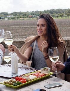 two people sitting at a table with glasses of wine and plates of food in front of them