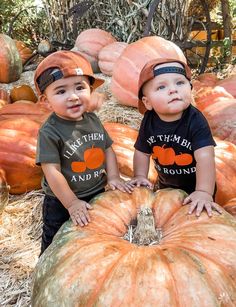 two young boys sitting on top of a pumpkin