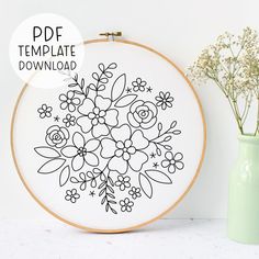 an embroidery pattern with flowers on it next to a vase