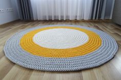 a round rug is on the floor in front of a window