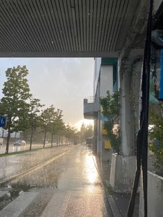 the sun is shining down on an empty street in the rain, with trees and buildings behind it