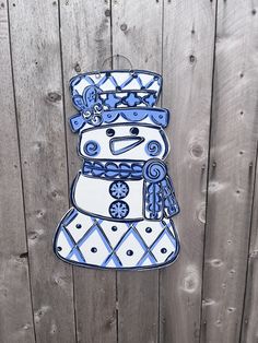 a wooden fence with a snowman made out of blue and white tiles on it