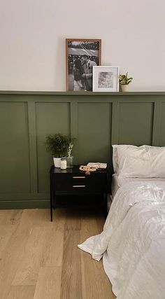 a bed sitting next to a green headboard on top of a hard wood floor