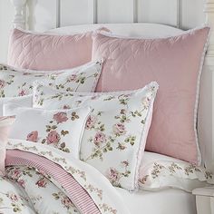 a white bed topped with pink and white pillows