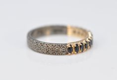 a close up of a ring on a white surface with gold and black stones in the middle